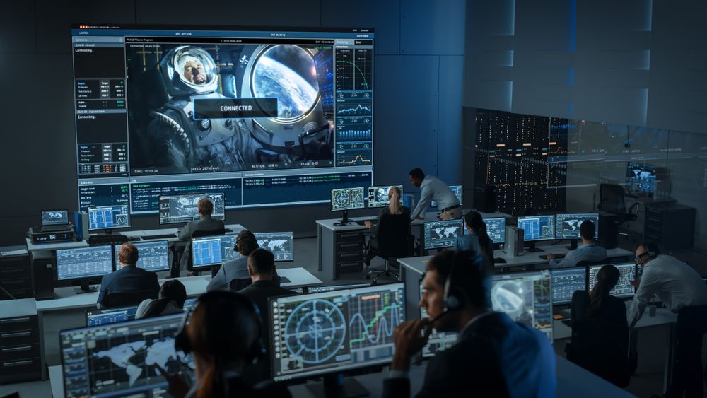 Mission Control Center Monitors Spacewalk. Large Screen Shows Astronaut With Earth View.