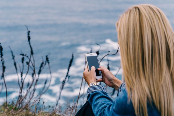 Female tourist taking shot of sea in twilight