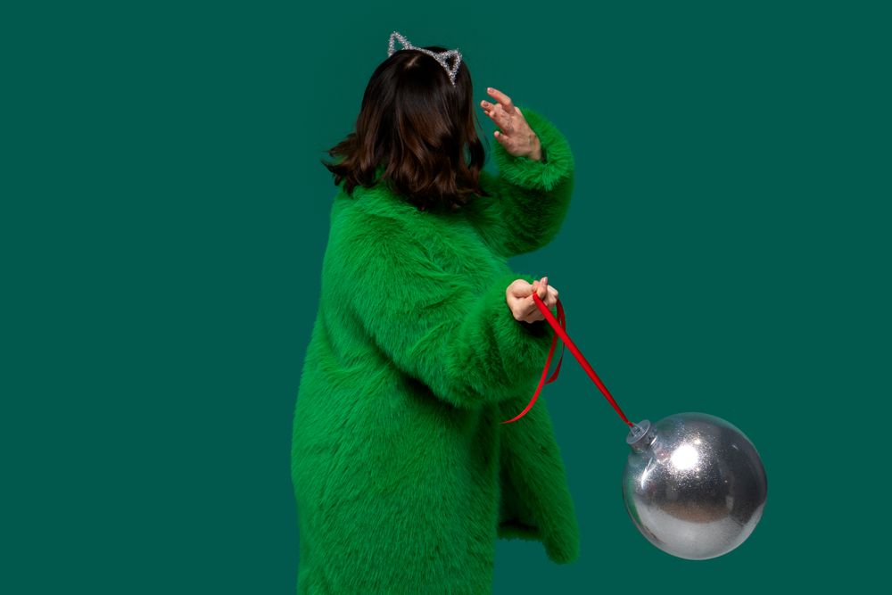 Woman holds large silver Christmas ornament.