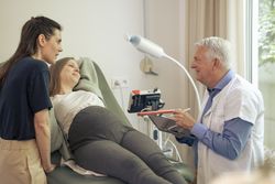 Doctor using a tablet during a consultation with a pregnant couple.