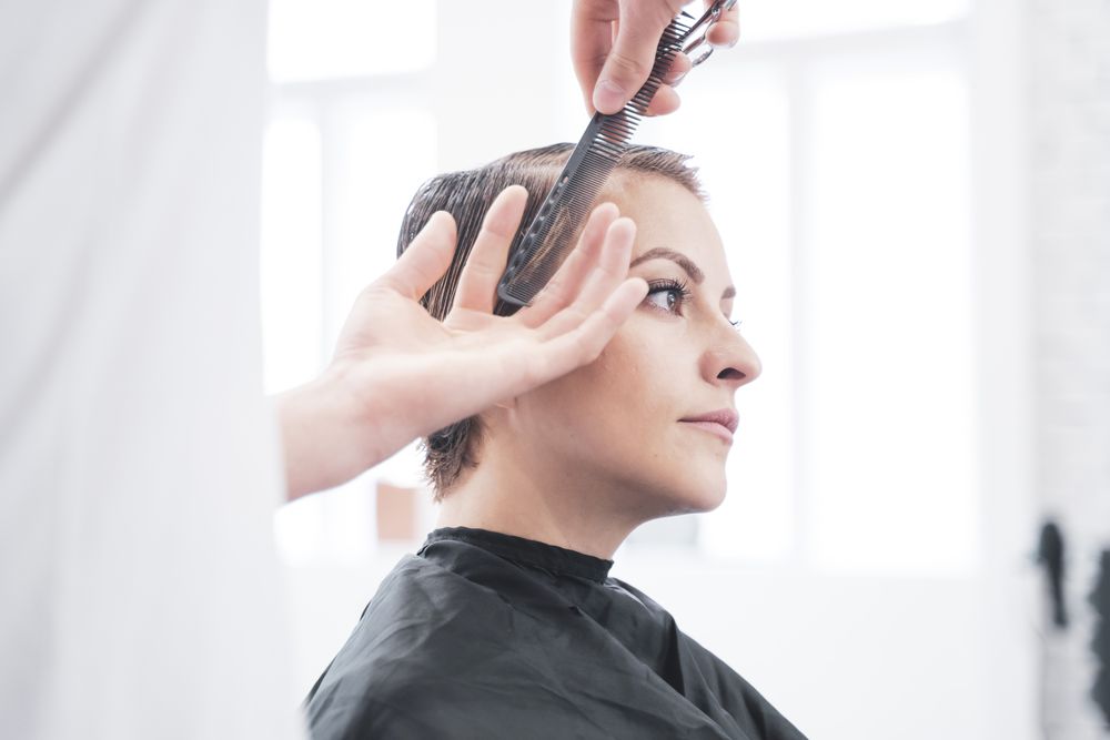 Hairdresser cuts woman's hair with scissors
