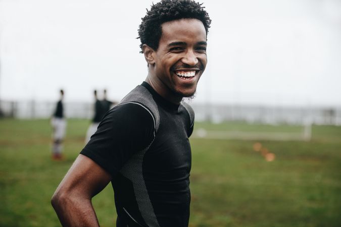 Portrait of a cheerful footballer standing on field during practice