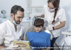 Male dentist shows structure of the tooth to little boy 0yWOj4