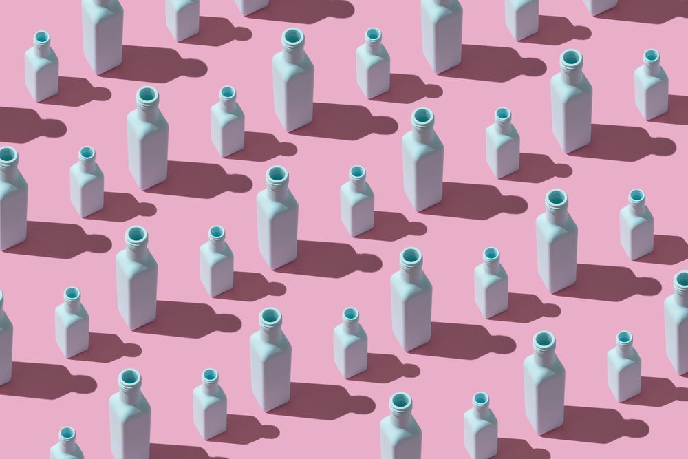 Rows of painted glass bottles on pink background