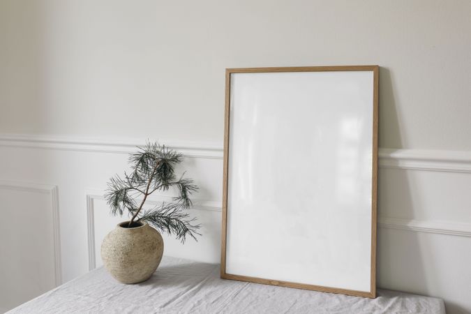 Blank vertical wooden picture frame mockup next to vase