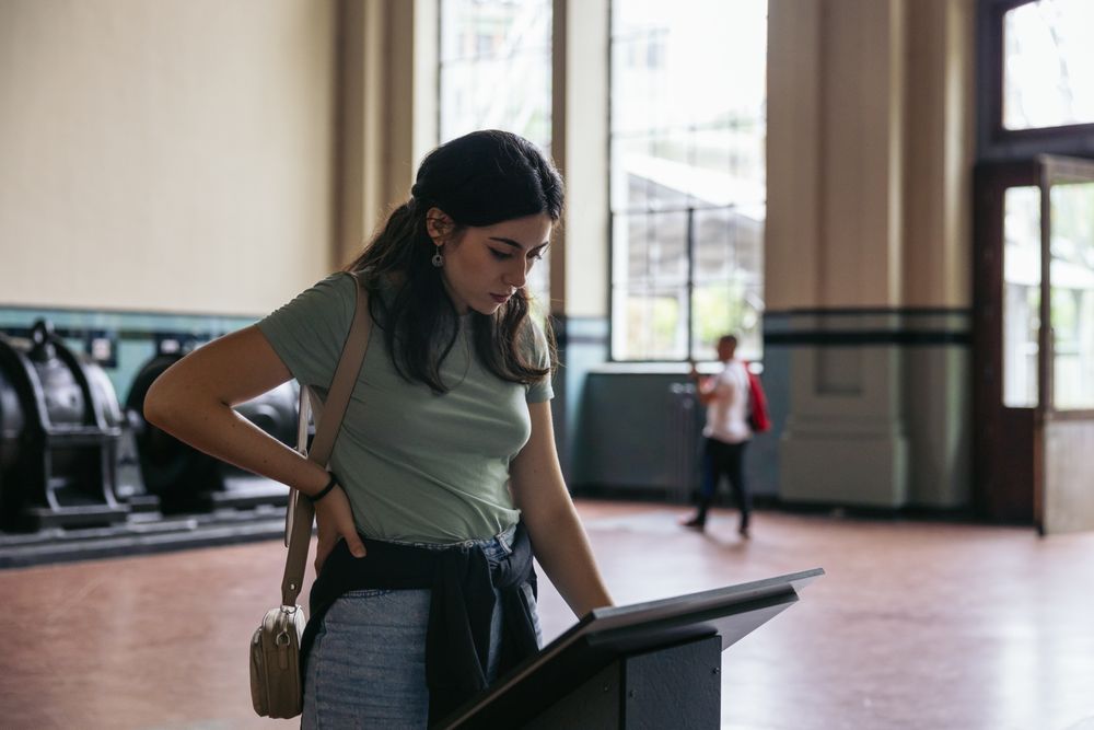 A woman stands reading an informational sign in a museum