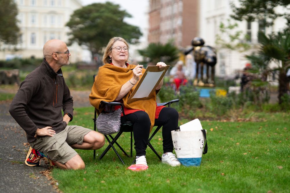 Woman sitting in park with art instructor