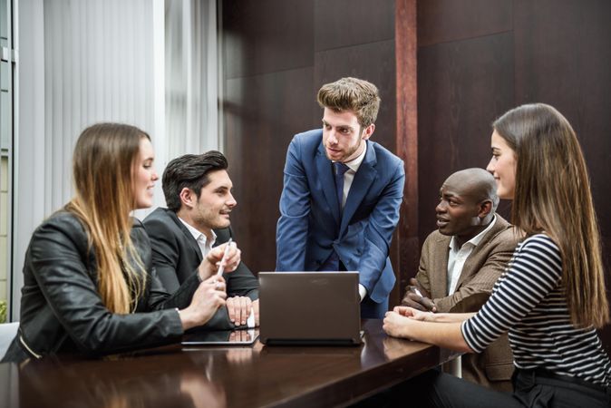 White man in business attire leading his colleagues in a brain storming meeting at work