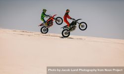Two motocross racers doing synchronized wheelie in desert 5rn1Z5