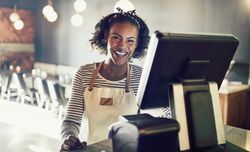 Happy woman at modern cash register taking orders in bistro