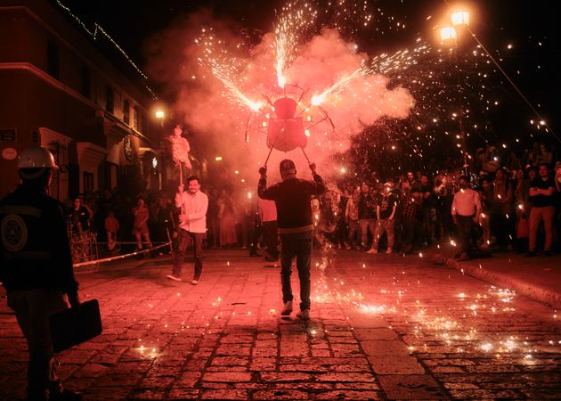 Man holding figure with fireworks at street festival