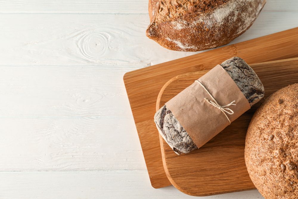 Bakery products and cutting boards on wooden background, top view and space for text