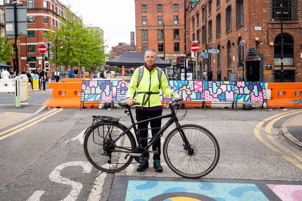 Older woman in neon wind breaker with her bicycle standing in the street