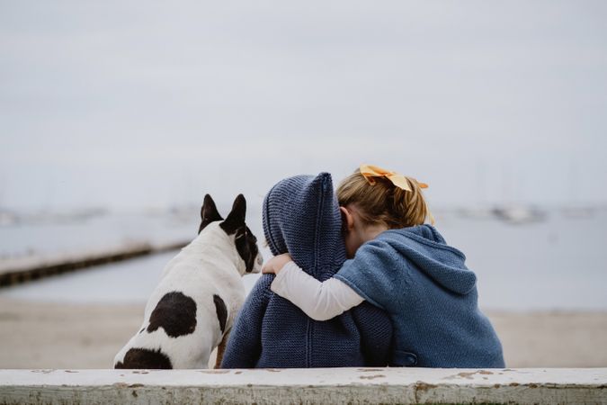 Kids hugging dog on beach