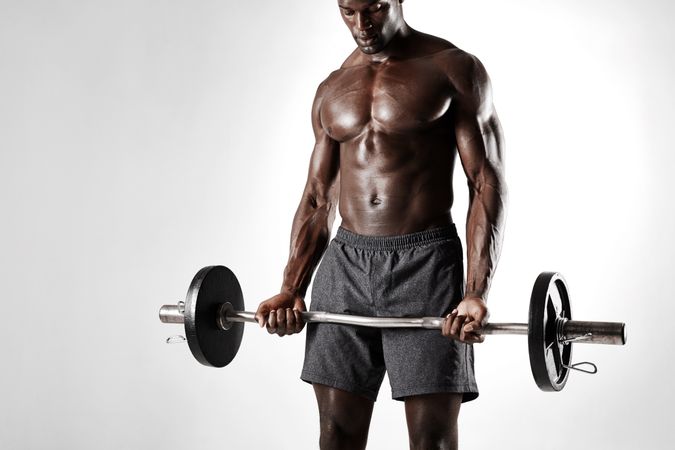 Black male fitness model exercising with barbell