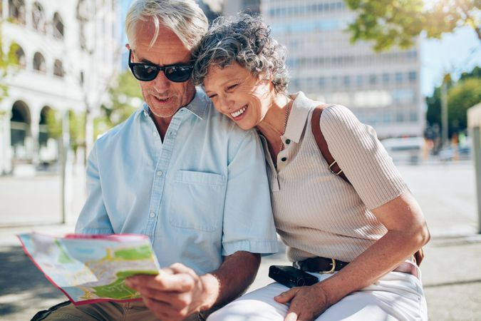 Happy mature couple looking at a city map on vacation