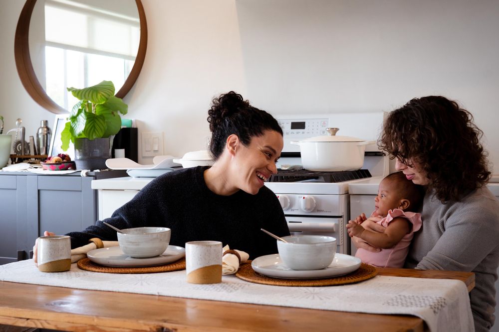 Two women eating soup with baby daughter at their dining table