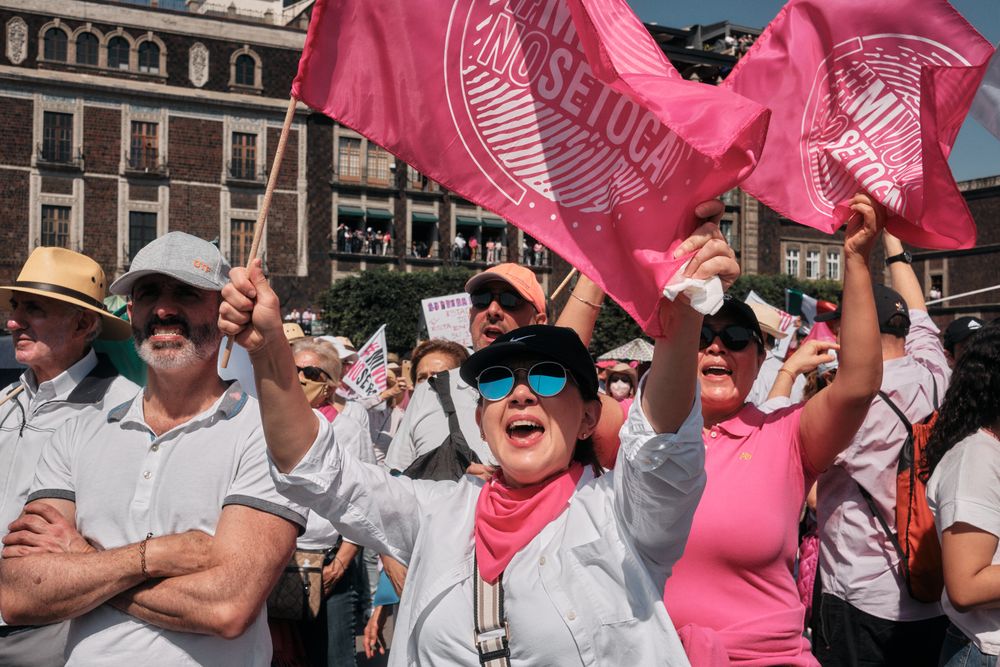 Mexico City, Mexico - February 26th, 2022: Happy woman in sunglasses holding up pink flag at protest
