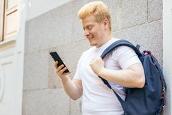 Latino man with albinism using smartphone in the city
