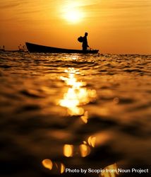 Man riding a boat in water during golden hour 4OZGR5