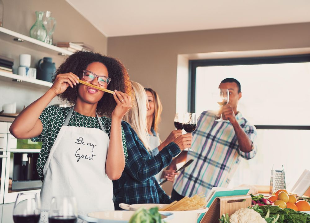 Multi-ethnic friends with wine and pasta in the kitchen