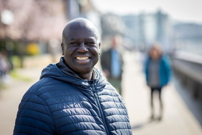 Black man walking by the river with two friends behind him