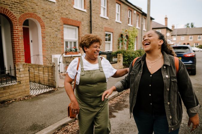 Two women laughing while walking down a residential street