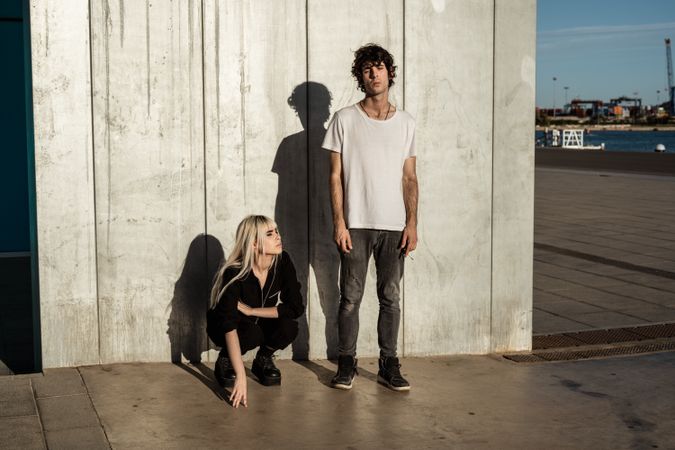 Rebellious trendy confident woman and calm guy against gray wall