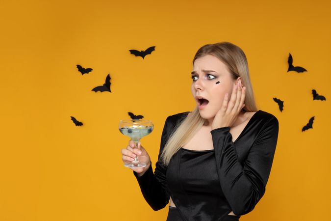 Concept of Halloween, young woman on yellow background