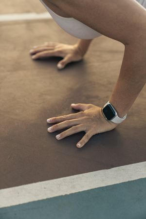 Close up of a woman's hands with a smartwatch in a plank position on a running track