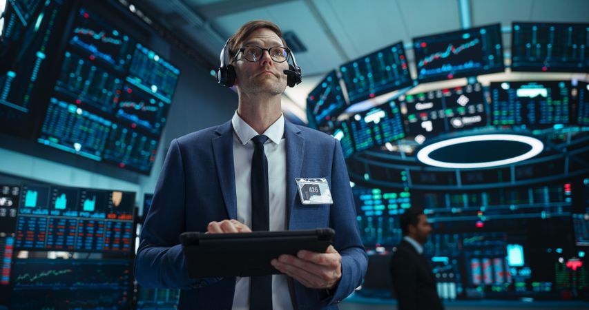 Portrait of a Young Stock Exchange Broker Using Tablet Computer, Researching Real-Time Stocks Data, Analyzing Commodities and Exchange Market Charts.
