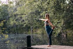 Woman in sportswear doing yoga outdoors near a lake