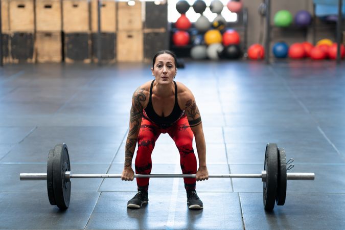 Woman dead-lifting in a cross training gym alone