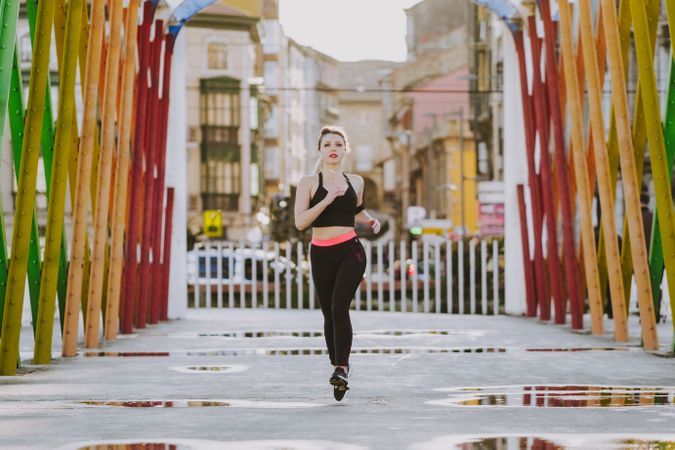 Woman with earphones running on street