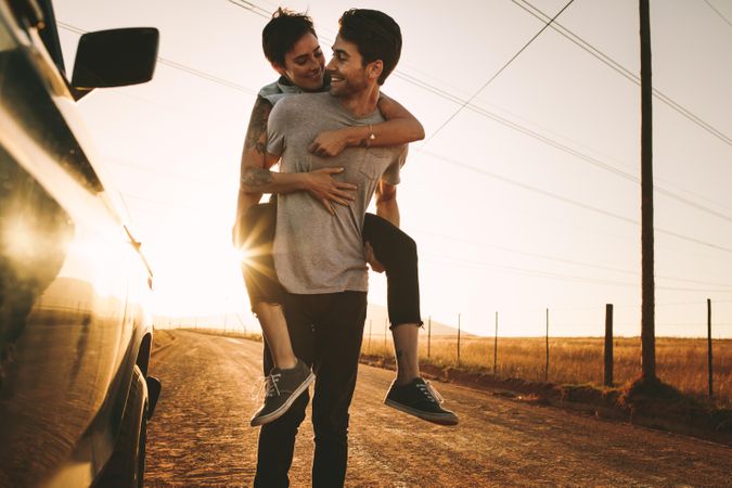 Playful couple having fun while on road trip through country side