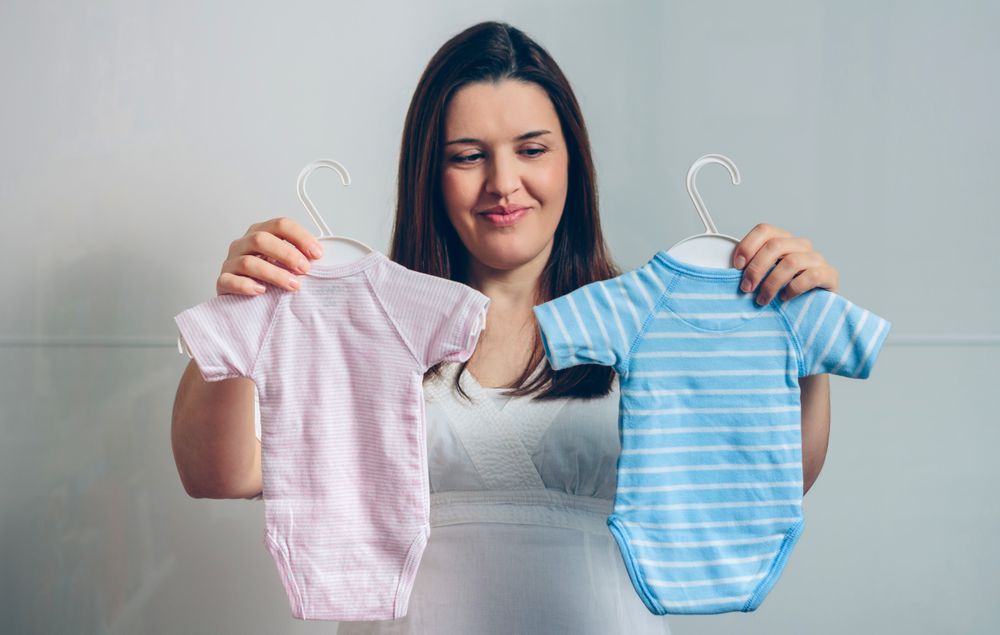 Pregnant woman choosing baby bodysuits