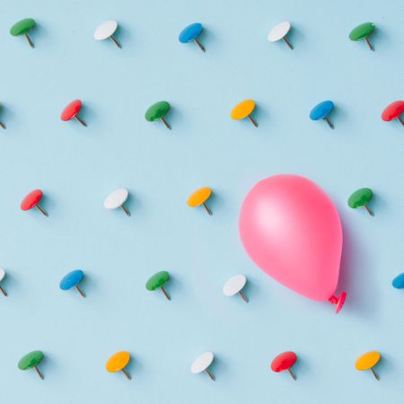 Colorful thumbtacks with balloon on blue background
