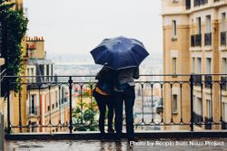 Backside of man and woman standing under umbrella while raining 5z6zQ5