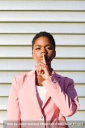 Female in pink suit making “shhh” gesture 4OmMg0