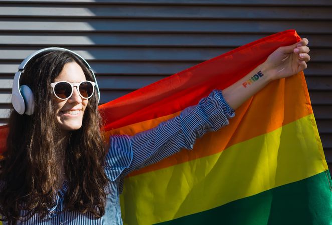 White female posing happily with the LGBT flag