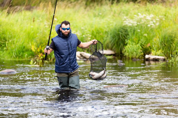 Fisherman crossing river with catch