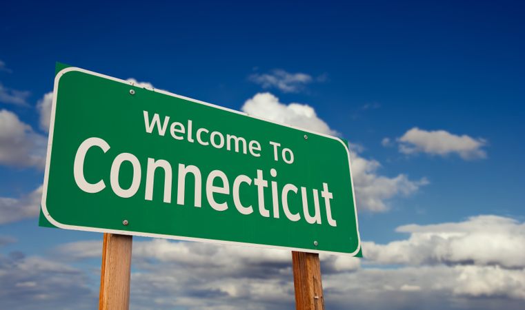 Welcome To Connecticut Green Road Sign Over Blue Sky with Some Clouds.
