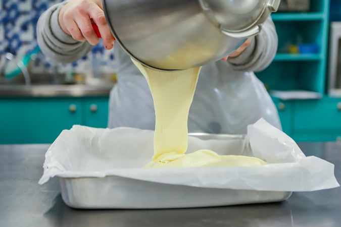 Cropped image of a person pouring soft dough into a mold