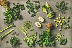 Arrangement of fresh green sliced garden vegetables on concrete surface