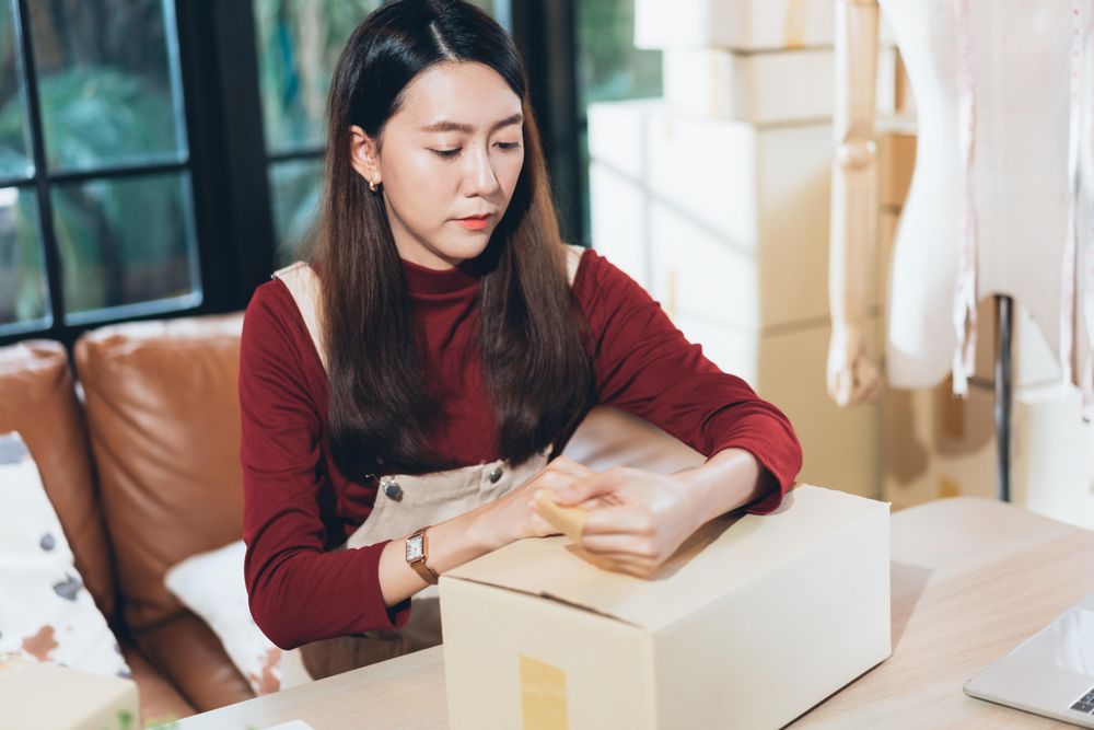 Woman closing a box at home