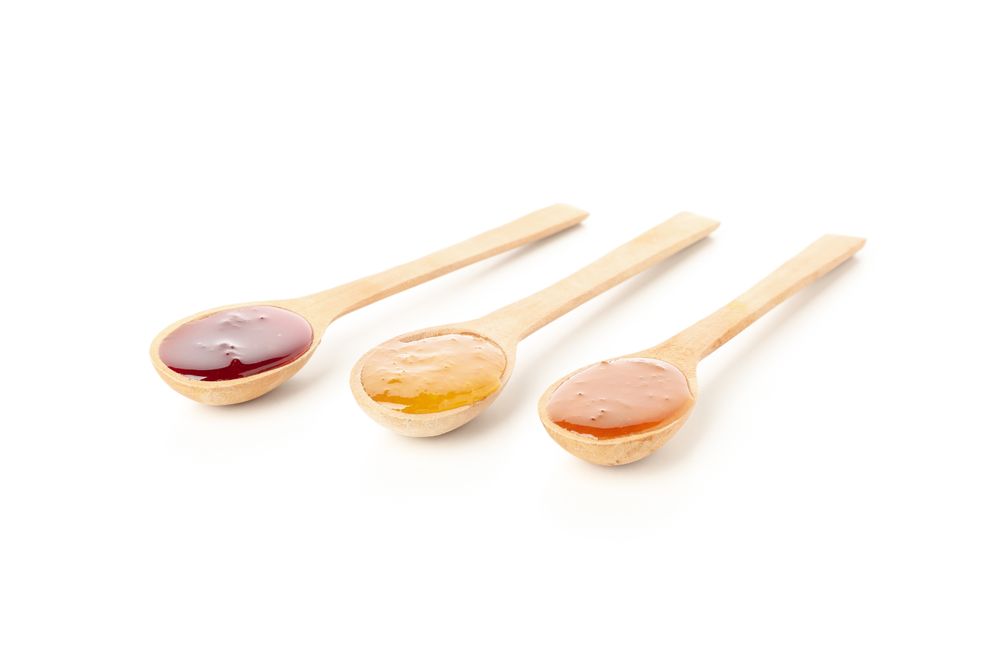 Spoons with jam isolated on plain background