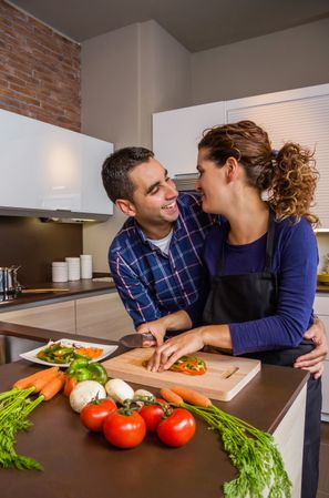 Couple talking together as they chop vegetables for meal