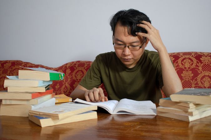Asian young male reading book with frustrated gesture