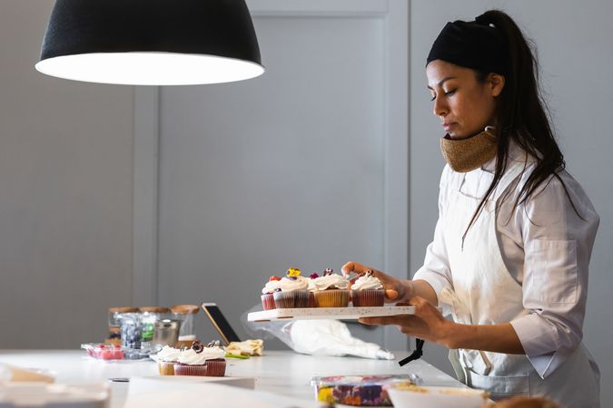 Female cook with cupcakes in kitchen