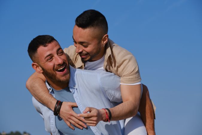 Happy gay couple playing piggyback
